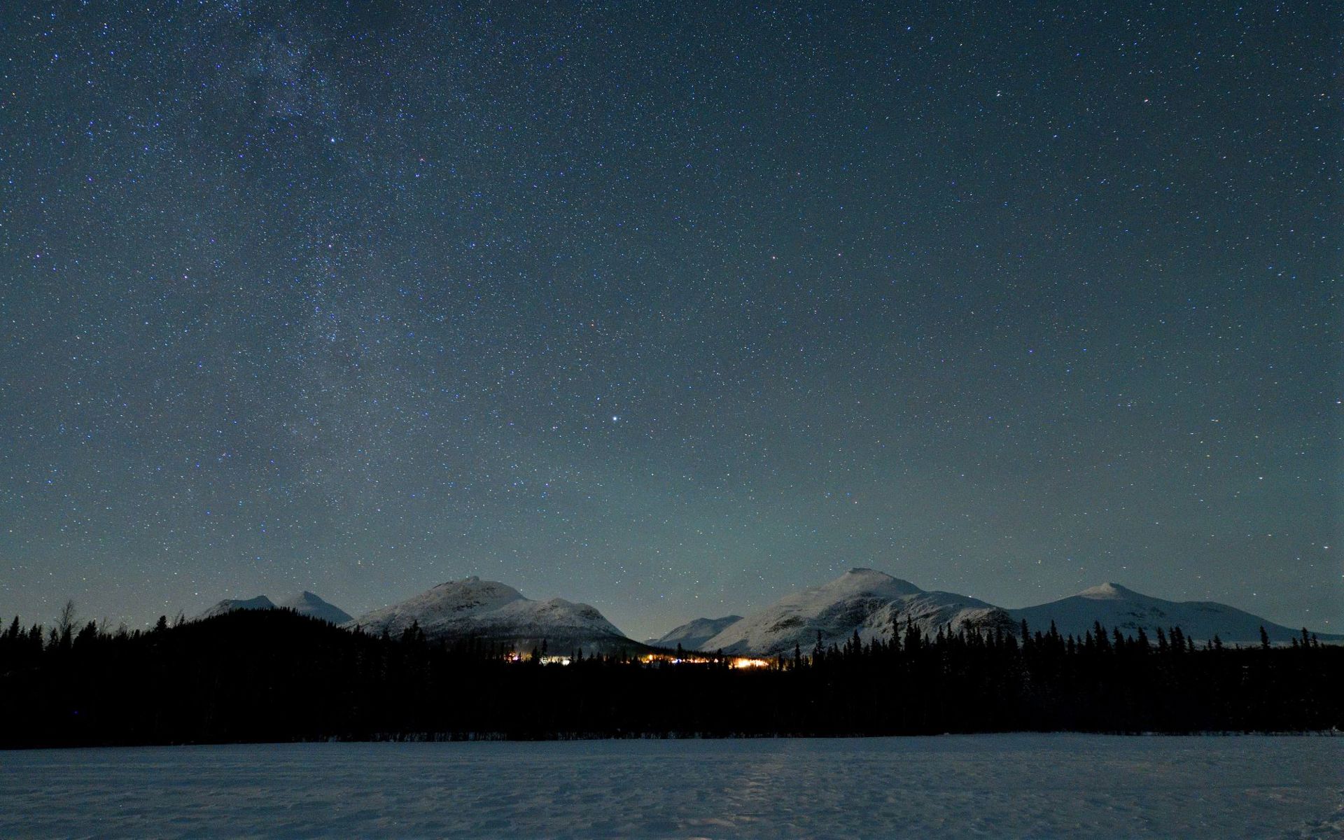 Photo: Ulf Mäkitalo A sky full of stars over white mountains and a small village.