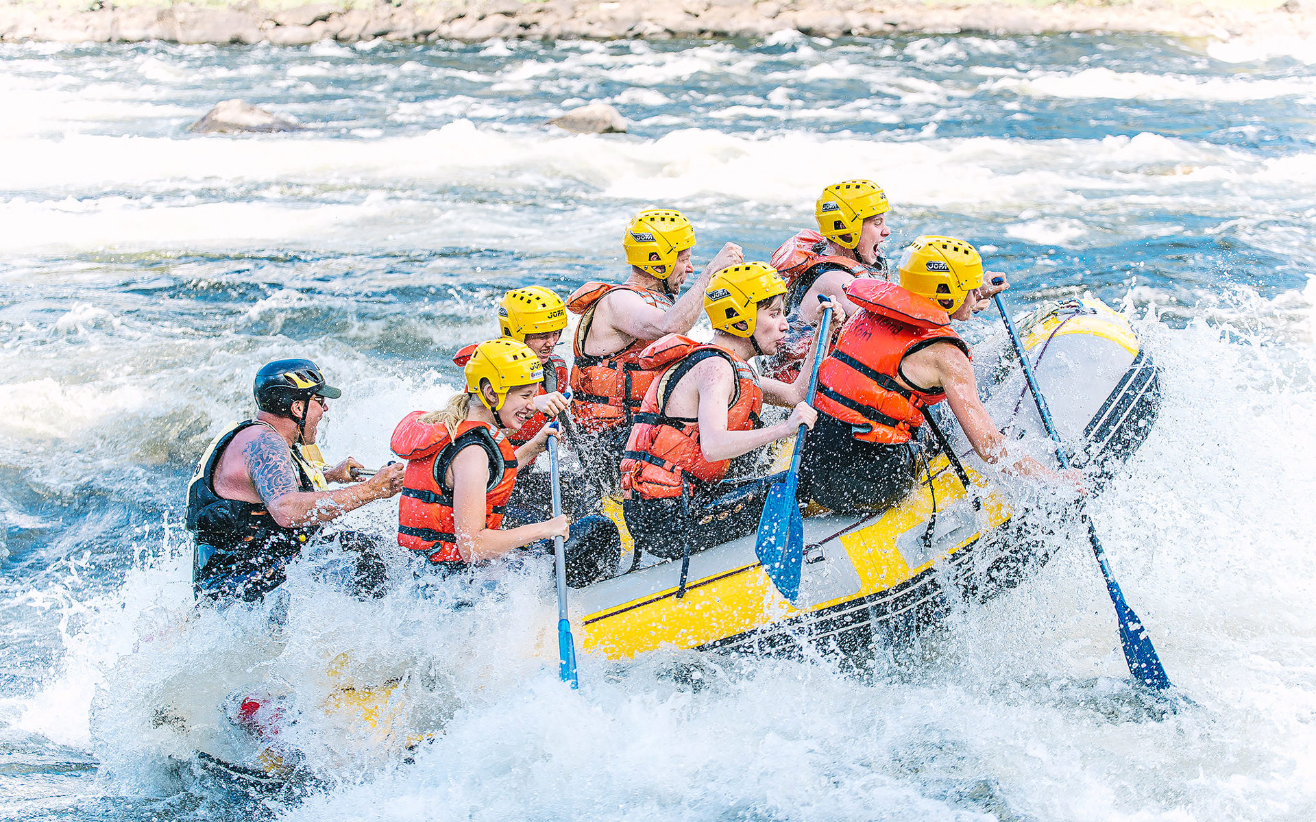 Photo: Visit Umeå People river rafting. Water splashing all around.
